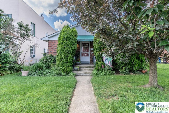 1919 W Cedar St Unit 1919, Allentown City, PA 18104 - view of property hidden behind natural elements featuring brick siding, a front yard, cooling unit, and stucco siding