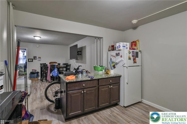 209 Cattell St, Easton, PA 18042 - kitchen with freestanding refrigerator, light wood finished floors, dark brown cabinets, light stone counters, and open floor plan