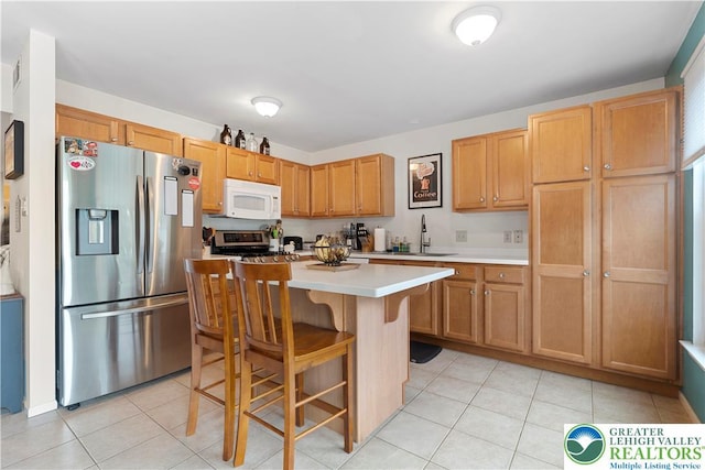 8067 Heritage Dr, Lower Macungie Twp, PA 18011 - kitchen with stainless steel appliances, light countertops, light tile patterned floors, and a kitchen breakfast bar