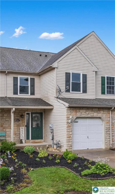 8067 Heritage Dr, Lower Macungie Twp, PA 18011 - view of front of house featuring stone siding, an attached garage, roof with shingles, and driveway