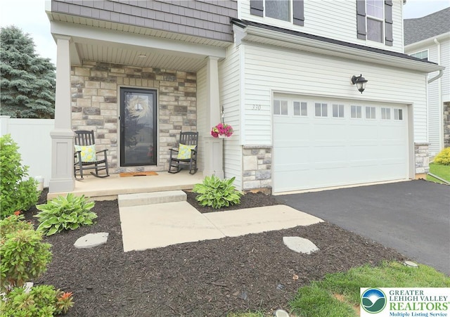 330 Bendelow Ln, Northampton Boro, PA 18067 - view of exterior entry featuring stone siding, a garage, covered porch, mansard roof, and asphalt driveway