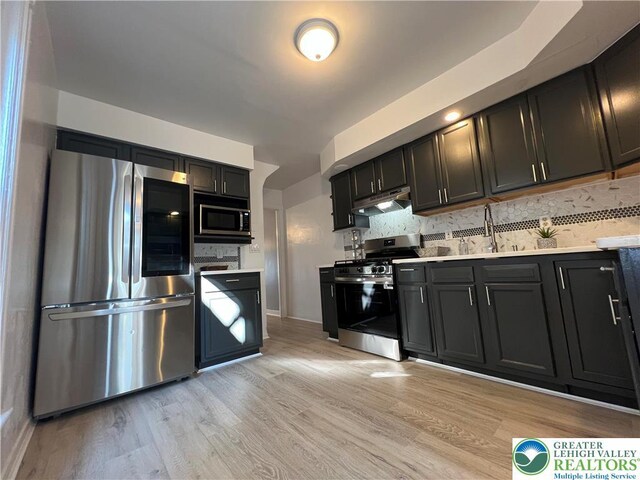 18 S Bradford St, Allentown City, PA 18109 - kitchen featuring appliances with stainless steel finishes, light countertops, light wood-style floors, under cabinet range hood, and decorative backsplash