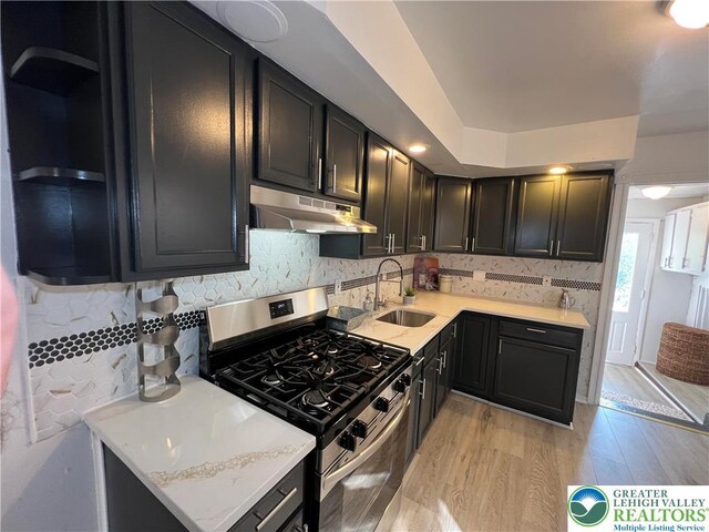 18 S Bradford St, Allentown City, PA 18109 - kitchen featuring gas stove, under cabinet range hood, backsplash, light wood-style flooring, and light countertops