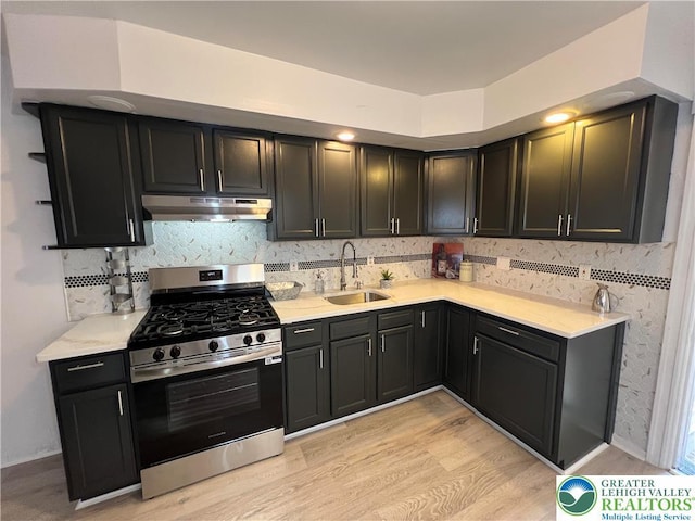 18 S Bradford St, Allentown City, PA 18109 - kitchen with stainless steel range with gas cooktop, under cabinet range hood, light wood-style floors, backsplash, and dark cabinetry