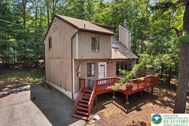 117 Manchester Dr, Lehman Twp, PA 18324 - rear view of property with a wooden deck, a shingled roof, a chimney, and view of wooded area