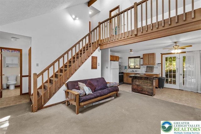 117 Manchester Dr, Lehman Twp, PA 18324 - living room featuring light colored carpet, high vaulted ceiling, stairway, ceiling fan, and french doors