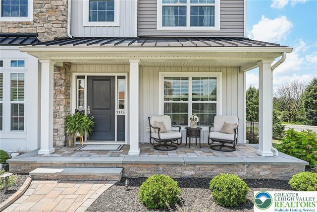 3334 Coventry Dr, Lower Macungie Twp, PA 18062 - property entrance with a porch, a standing seam roof, a metal roof, and stone siding