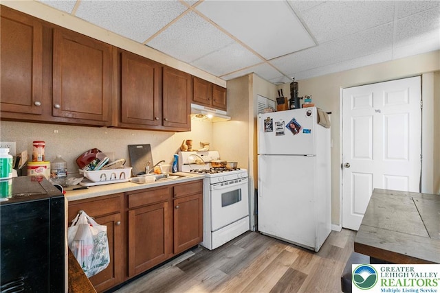 1002 S 6th St, Allentown City, PA 18103 - kitchen featuring white appliances, under cabinet range hood, a paneled ceiling, brown cabinets, and light wood-type flooring