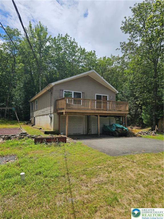 178 Sparrow Ln, Penn Forest Twp, PA 18229 - view of front facade with asphalt driveway, a wooden deck, a front lawn, and an attached garage