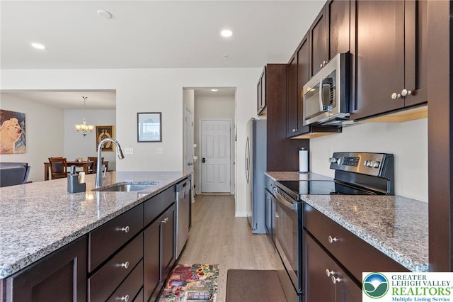 4435 Benjamin Ct, Upper Milford Twp, PA 18049 - kitchen featuring appliances with stainless steel finishes, dark brown cabinets, light stone countertops, light wood-style floors, and a chandelier