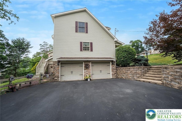 2300 Woodridge Ter, Easton, PA 18045 - view of side of property featuring stone siding, driveway, stairway, and a garage