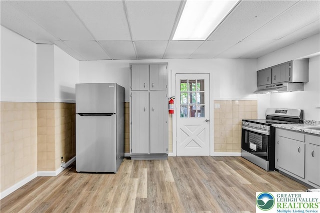 133 S 14th St, Easton, PA 18042 - kitchen with appliances with stainless steel finishes, under cabinet range hood, gray cabinets, light wood-style flooring, and wainscoting