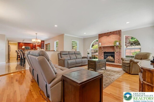 1376 Buck Ridge Dr, Hamilton Twp, PA 18360 - living area with a chandelier, light wood-style flooring, a brick fireplace, crown molding, and recessed lighting