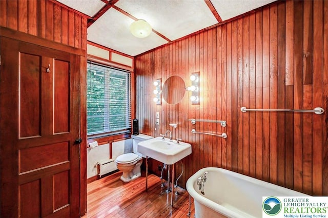 664 Griscom Rd, Barrett Twp, PA 18323 - bathroom featuring a freestanding tub, wood finished floors, a baseboard heating unit, and wood walls