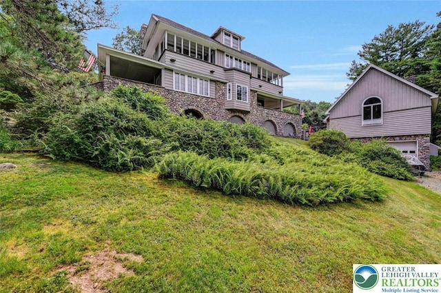 664 Griscom Rd, Barrett Twp, PA 18323 - back of property featuring stone siding, a lawn, and an attached garage