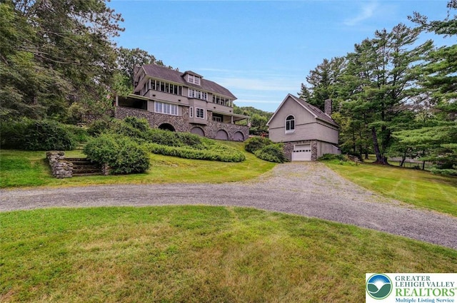 664 Griscom Rd, Barrett Twp, PA 18323 - view of front facade with dirt driveway, a garage, a front yard, a chimney, and stone siding
