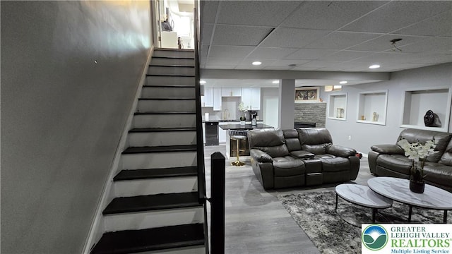 1136 Ashbourne Dr, Muhlenberg Twp, PA 19605 - living room featuring stairway, light wood-type flooring, a drop ceiling, a fireplace, and recessed lighting