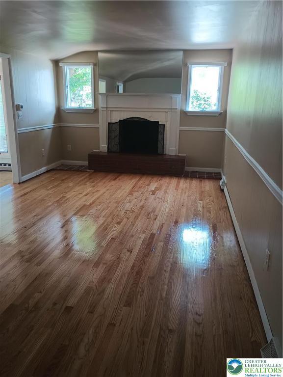 6059 Clubhouse Ln, Lower Macungie Twp, PA 18106 - unfurnished living room with wood finished floors, a fireplace with raised hearth, healthy amount of natural light, and lofted ceiling