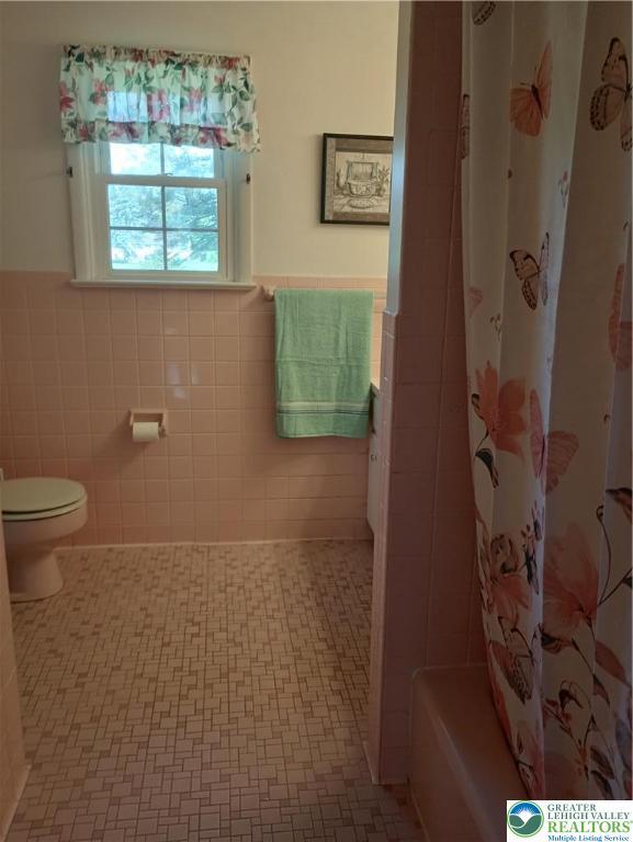 6059 Clubhouse Ln, Lower Macungie Twp, PA 18106 - bathroom featuring tile walls, wainscoting, and shower / bathtub combination with curtain