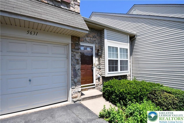 5631 Stonecroft Ln, Lower Macungie Twp, PA 18106 - entrance to property featuring stone siding, a garage, asphalt driveway, and a shingled roof
