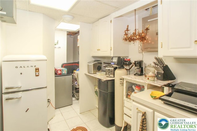 518 Bauer Rd, Moore Twp, PA 18014 - kitchen featuring freestanding refrigerator, white cabinetry, light countertops, light tile patterned floors, and a drop ceiling