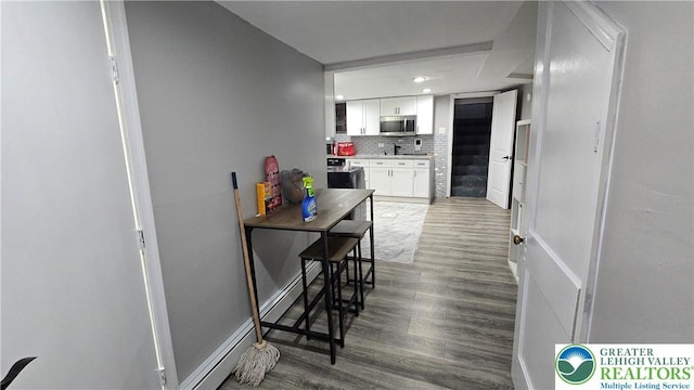 1500 Schuylkill Ave, Reading City, PA 19601 - kitchen featuring stainless steel microwave, tasteful backsplash, wood finished floors, white cabinets, and light countertops