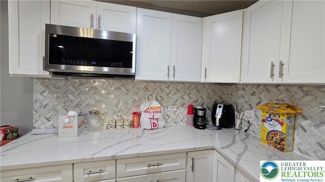 1500 Schuylkill Ave, Reading City, PA 19601 - kitchen with stainless steel microwave, white cabinets, backsplash, and light stone countertops
