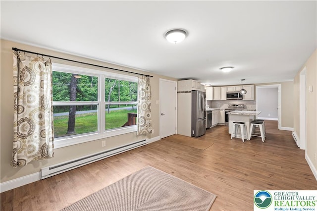 29 Long Brook Way, Penn Forest Twp, PA 18210 - kitchen featuring baseboard heating, stainless steel appliances, tasteful backsplash, a kitchen bar, and light wood-type flooring