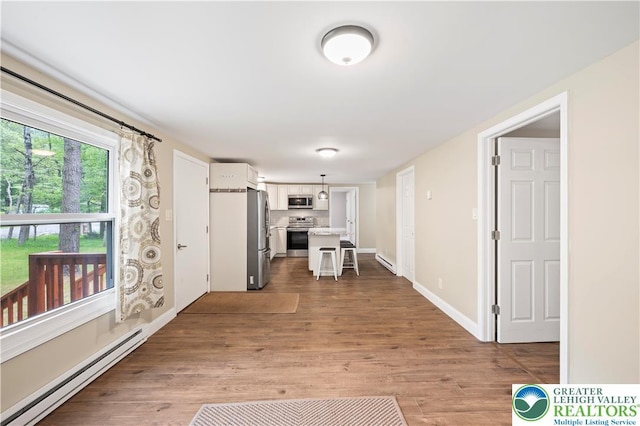 29 Long Brook Way, Penn Forest Twp, PA 18210 - kitchen featuring a baseboard radiator, appliances with stainless steel finishes, light countertops, light wood-type flooring, and a breakfast bar