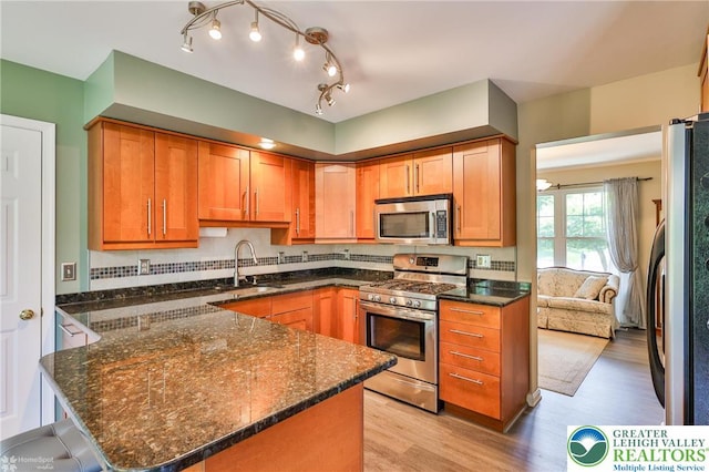 1945 Jenkins Dr, Forks Twp, PA 18040 - kitchen with stainless steel appliances, dark stone counters, light wood-style flooring, a peninsula, and brown cabinets