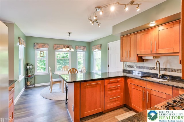 1945 Jenkins Dr, Forks Twp, PA 18040 - kitchen with a chandelier, a peninsula, light wood-style floors, brown cabinets, and dark stone counters