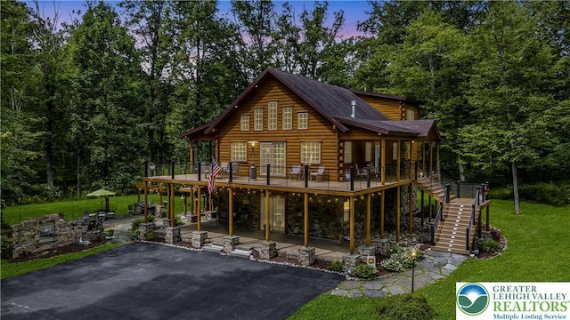 207 W Douglasville Rd, Bushkill Twp, PA 18064 - back of property at dusk with stairs, a patio area, log exterior, a deck, and a lawn