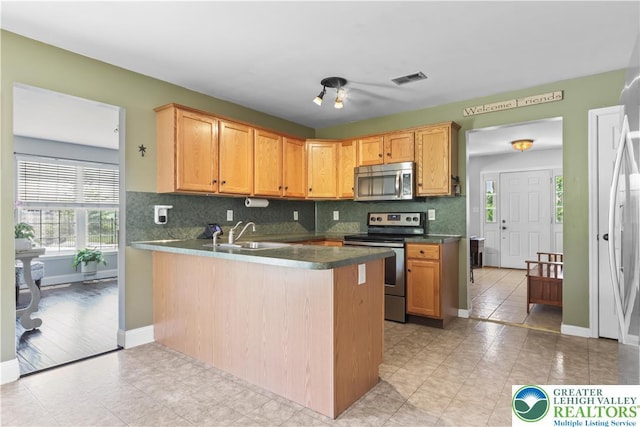 7725 Harbor Ct, Washington Twp, PA 18080 - kitchen featuring stainless steel appliances, tasteful backsplash, a peninsula, dark countertops, and light tile patterned flooring