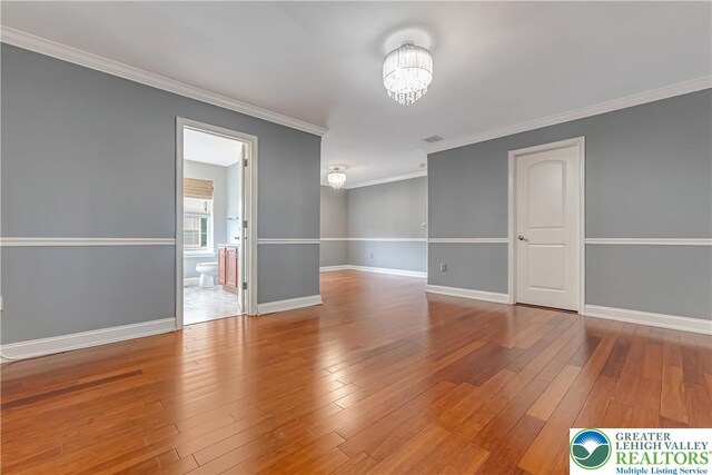 6945 Hunt Dr, Lower Macungie Twp, PA 18062 - empty room with a chandelier, hardwood / wood-style floors, and crown molding