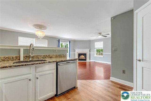 6945 Hunt Dr, Lower Macungie Twp, PA 18062 - kitchen with stainless steel dishwasher, light wood-style floors, ceiling fan, white cabinetry, and a fireplace with flush hearth