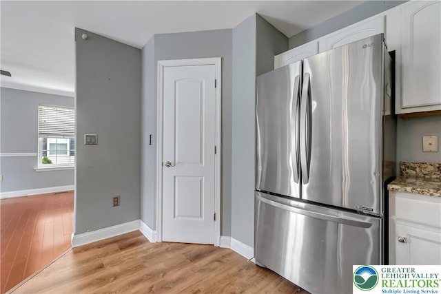 6945 Hunt Dr, Lower Macungie Twp, PA 18062 - kitchen with freestanding refrigerator, white cabinetry, light wood-type flooring, and light stone counters