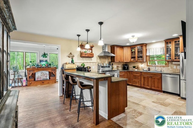 1079 Marshalls Creek Rd, Middle Smithfield Twp, PA 18302 - kitchen with appliances with stainless steel finishes, wall chimney exhaust hood, brown cabinets, a peninsula, and a kitchen bar