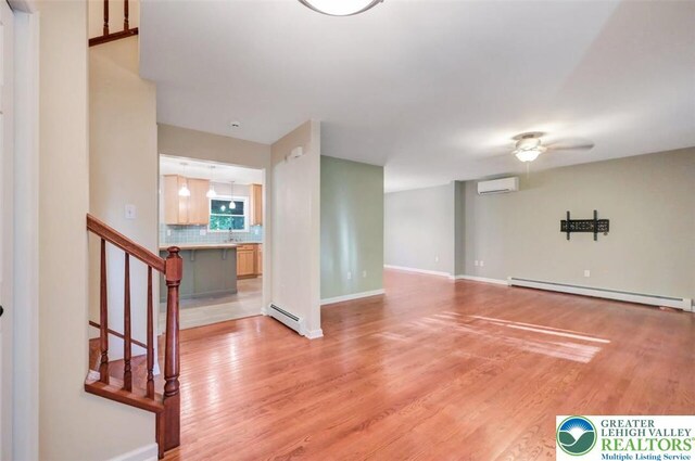 119 Savage Trl, Smithfield Twp, PA 18301 - unfurnished living room featuring a baseboard heating unit, a wall mounted AC, and light wood finished floors
