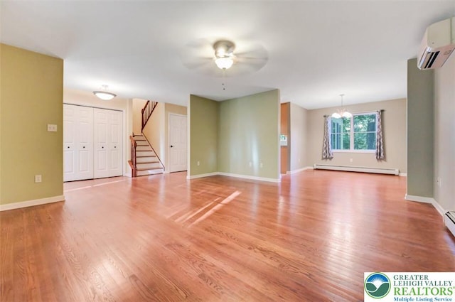119 Savage Trl, Smithfield Twp, PA 18301 - unfurnished living room featuring baseboard heating, a wall unit AC, ceiling fan, stairs, and light wood-style floors