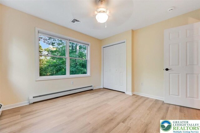 119 Savage Trl, Smithfield Twp, PA 18301 - unfurnished bedroom featuring a baseboard radiator, light wood-style flooring, a closet, and a ceiling fan