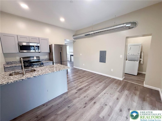 801 W Broad, Bethlehem City, PA 18018 - kitchen featuring stainless steel appliances, stacked washer / dryer, electric panel, light stone counters, and light wood-style flooring