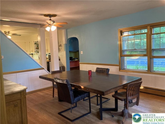 5984 Rte 412, Springfield Twp, PA 18077 - dining area with ceiling fan, arched walkways, a baseboard heating unit, wood finished floors, and a wainscoted wall