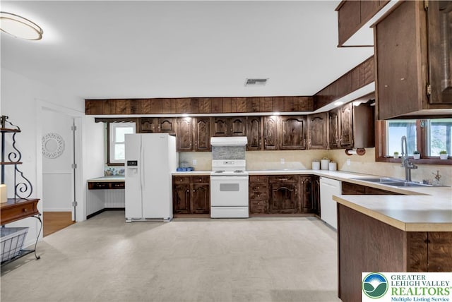 8555 Mohr Ln, Weisenberg Twp, PA 18051 - kitchen featuring white appliances, under cabinet range hood, dark brown cabinetry, and decorative backsplash