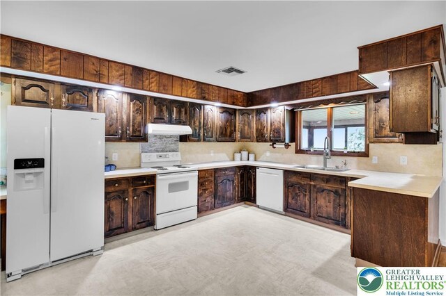 8555 Mohr Ln, Weisenberg Twp, PA 18051 - kitchen with white appliances, under cabinet range hood, dark brown cabinets, light countertops, and backsplash