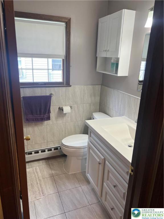 5129 3rd St, Whitehall Twp, PA 18052 - bathroom featuring baseboard heating, tile walls, vanity, tile patterned floors, and wainscoting