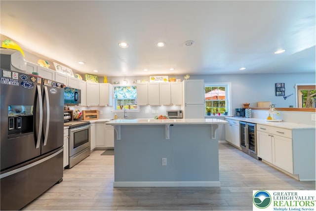 2175 Village Rd, Chestnuthill Twp, PA 18330 - kitchen featuring appliances with stainless steel finishes, wine cooler, light wood-style floors, light countertops, and a breakfast bar area