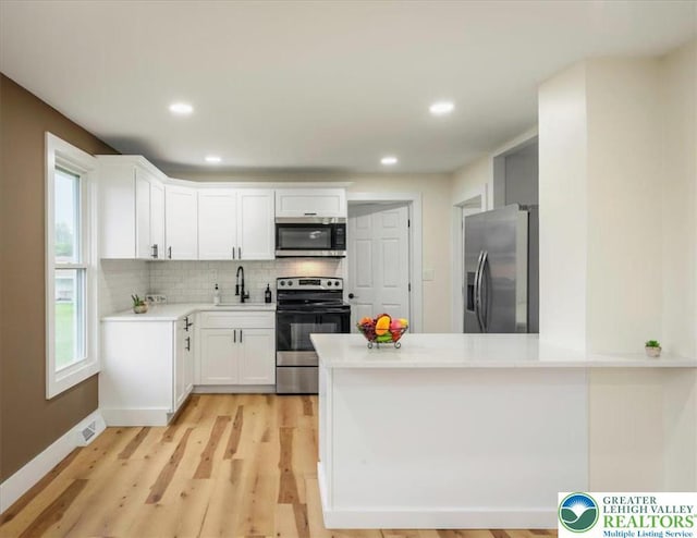 428 Shook Ave, Stroud Twp, PA 18360 - kitchen featuring stainless steel appliances, tasteful backsplash, white cabinets, light countertops, and light wood-style flooring