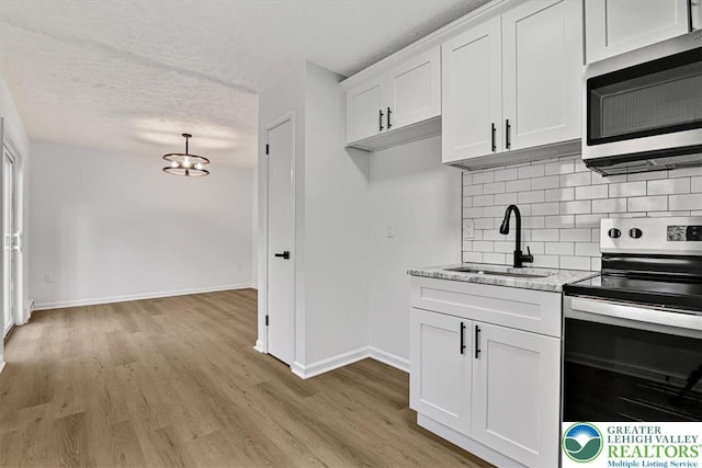 182 Maxatawny Dr, Coolbaugh Twp, PA 18347 - kitchen featuring stainless steel appliances, a textured ceiling, backsplash, light wood-style floors, and white cabinetry