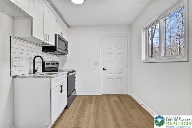 182 Maxatawny Dr, Coolbaugh Twp, PA 18347 - kitchen featuring appliances with stainless steel finishes, light wood-style flooring, tasteful backsplash, white cabinets, and light stone countertops