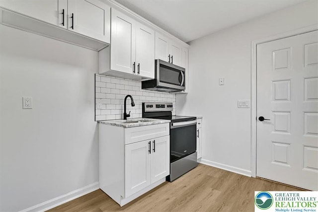 182 Maxatawny Dr, Coolbaugh Twp, PA 18347 - kitchen with appliances with stainless steel finishes, light wood-style flooring, backsplash, white cabinetry, and light stone counters